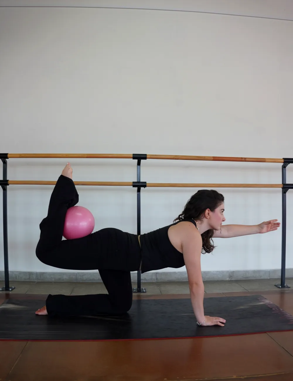 Alumna en la barra haciendo un ejercicio de barre en el studio ivi.